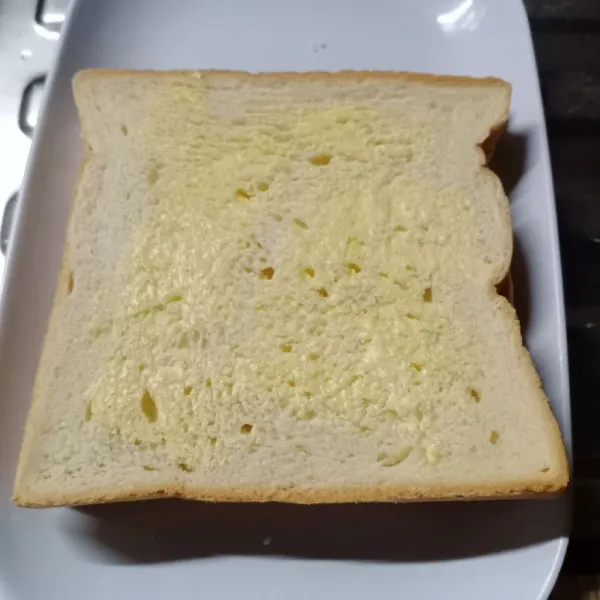 Kemudian tutup dengan roti. Oles permukaan roti dengan margarin.