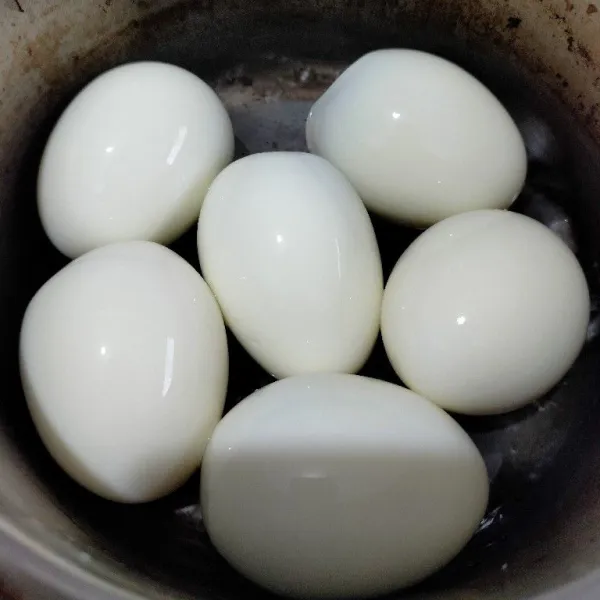 Rebus telur hingga matang lalu kupas kulitnya.