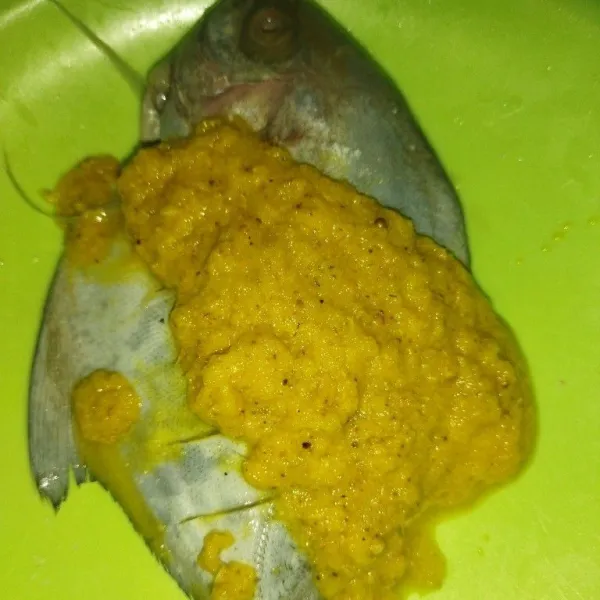 Haluskan bawang merah, bawang putih, ketumbar, jahe dan kunyit, lalu tuang bumbu ke wadah yang berisi ikan.