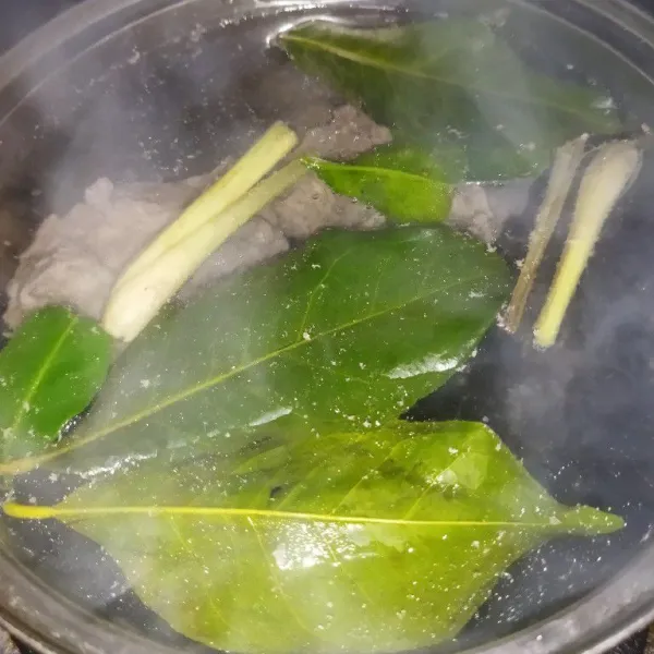 Masak air hingga mendidih, lalu masukkan daging sapi, jahe, daun salam, daun jeruk dan serai, tutup pancinya, rebus hingga daging empuk.