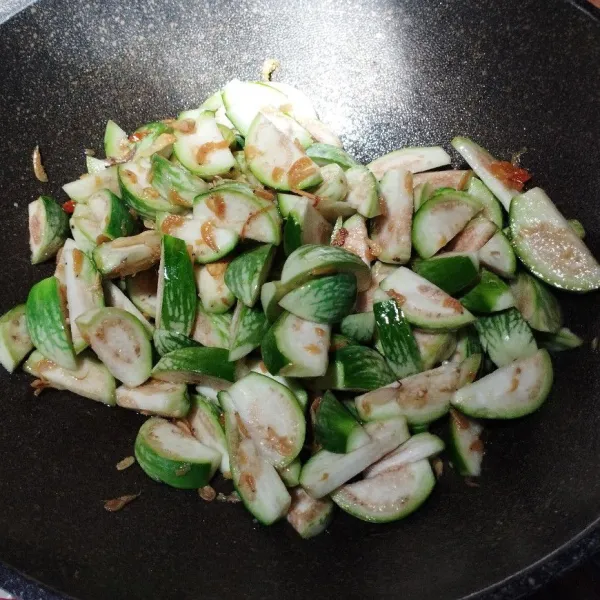 Masukkan terong bulat. aduk-aduk sampai tercampur dengan bumbu. Tambahkan garam, gula, kaldu bubuk, lada bubuk, dan kecap. Aduk rata. Masak sampai terong setengah layu. Koreksi rasa.