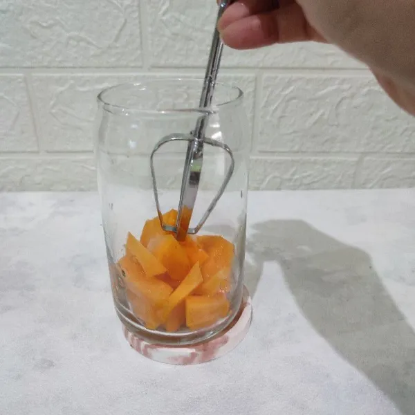 Potong kecil-kecil mangga lalu masukkan ke dalam gelas saji kemudian hancurkan dengan whisk atau sendok.