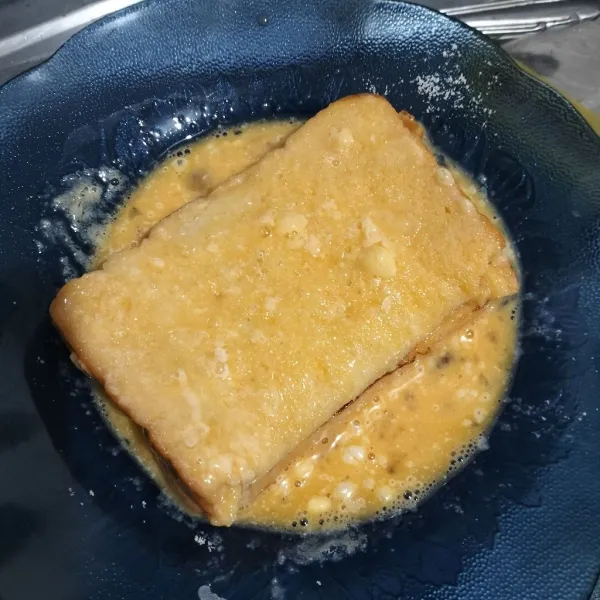 Lalu balur seluruh roti dengan telur kocok.