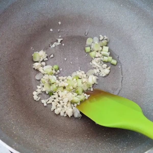 Panaskan minyak, tumis bawang putih cincang dan bagian putih daun bawang hingga harum.