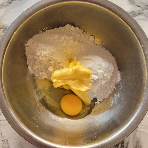 Untuk membuat topping atasnya, campurkan mentega sebanyak 60 gram, gula halus, tepung terigu, dan telur, lalu mixer hingga tercampur rata