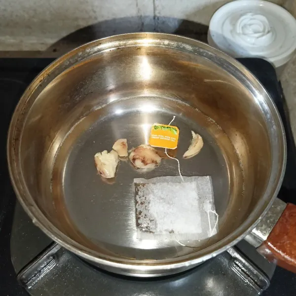 Dalam panci berisi air, rebus jahe dan teh hitam