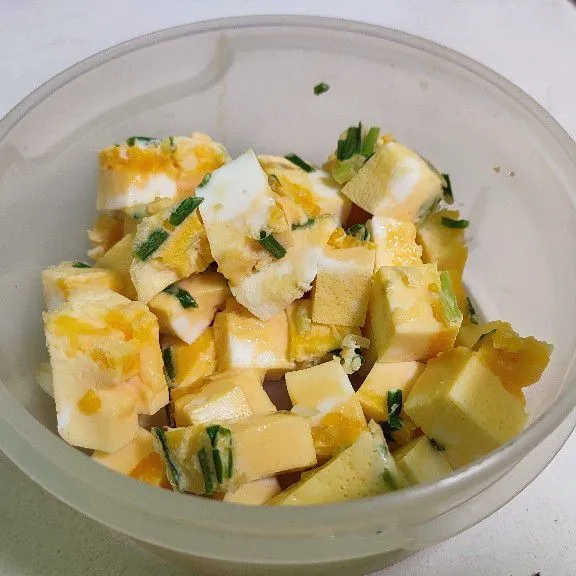 Aduk telur dalam wadah, tambahkan irisan daun bawang, kukus lalu potong dadu .