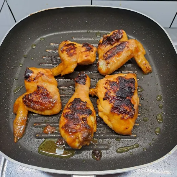 Panaskan grill pan, oles minyak goreng. Bakar ayam sampai sedikit kecoklatan sambil dioles sisa bumbu ungkep. Angkat dan sajikan.