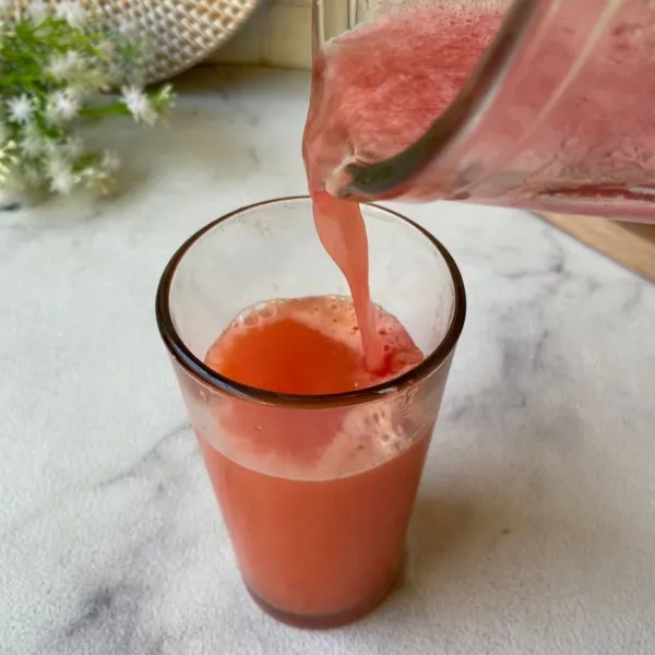 Tuang jus semangka ke dalam gelas yang berisi sari jeruk. Jus siap disajikan.