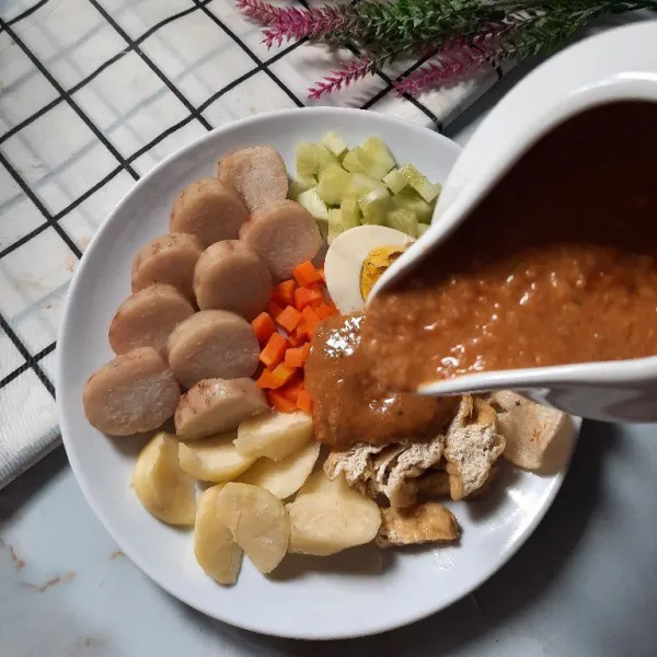 Tuang saus kacang di atas pelengkap, gado-gado siap disajikan.