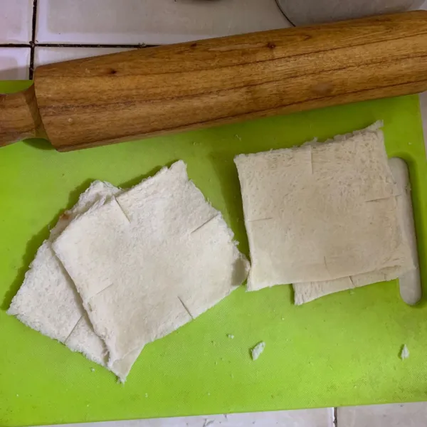 Pipihkan roti tawar menggunakan rolling pin, potong sedikit keempat sisi tengah roti tawar (jangan sampai putus)