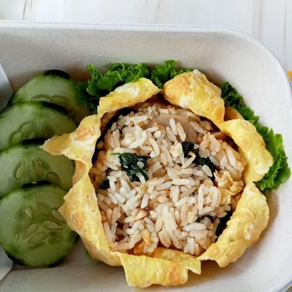 Masukkan nasi ke dalam kotak nasi tambahkan selada dan mentimun, juga minuman kesehatan. Bekal siap dinikmati.