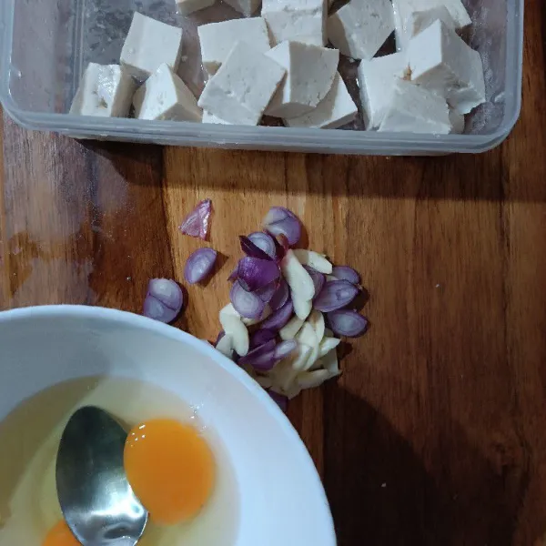 Siapkan bahan. Iris dua bawang, potong kotak tahu, dan kocok telur.