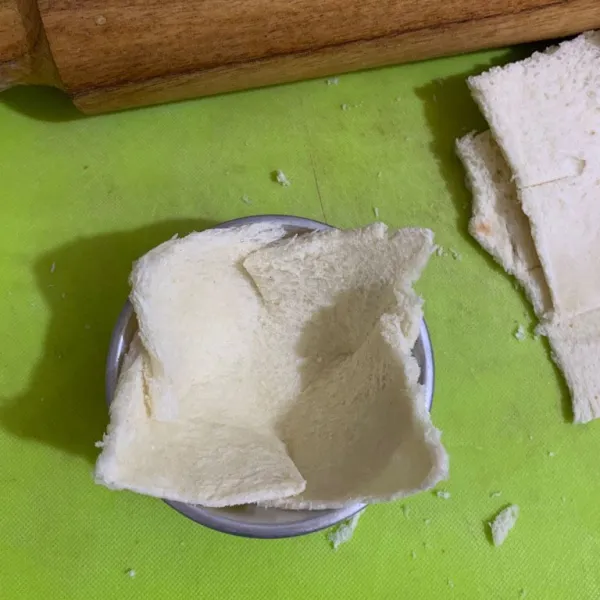 Lipat saling menumpuk keempat sisi roti tawar dan letakkan dalam cetakan
