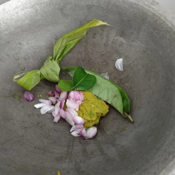 Masukkan bumbu halus, daun jeruk, daun salam, daun kunyit, dan bawang merah yang sudah diiris ke dalam wajan.