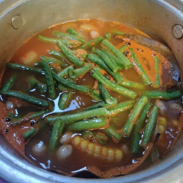Masukkan kacang panjang, gula merah, garam dan kaldu blok. Aduk.