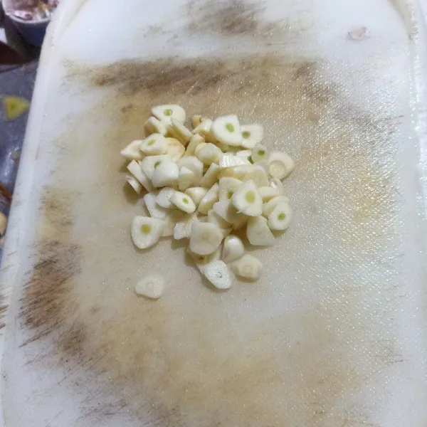Kupas bawang putih lalu iris tipis.