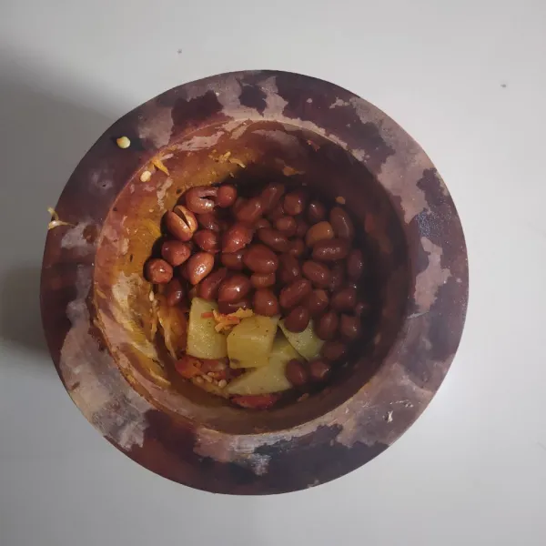 Haluskan bawang putih, kencur dan cabe rawit, kemudian haluskan kacang tanah goreng, gula jawa, garam dan kentang, beri sedikit air jika terlalu kental.