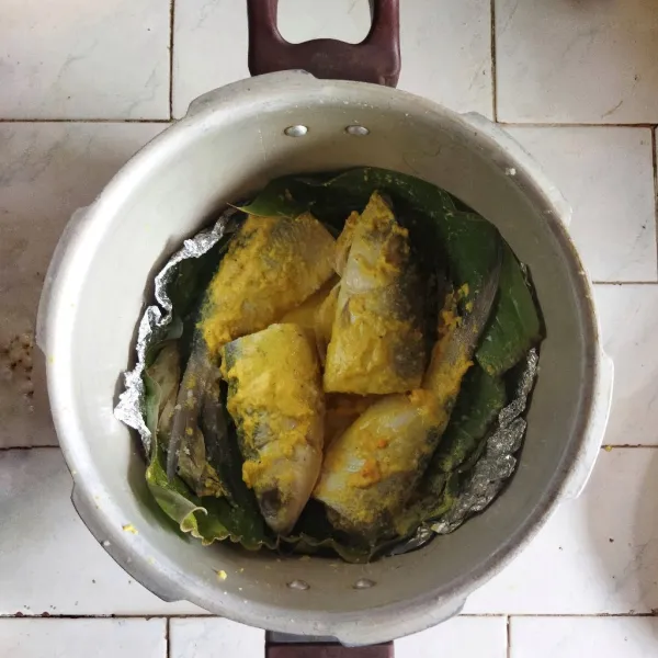 Siapkan panci presto. Alasi dasarnya dengan daun, letakkan beberapa bumbu aromatik. Tata ikan bandeng di dalam panci, jangan lupa untuk meletakkan bumbu aromatik di sekitarnya.