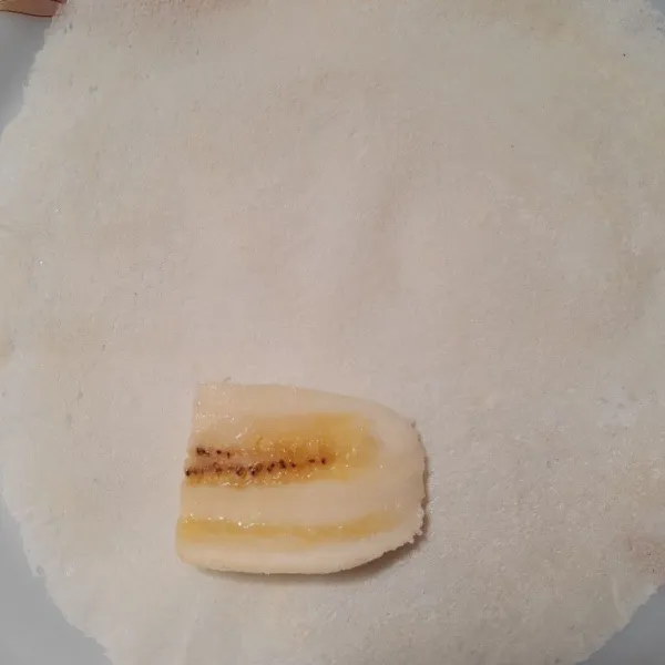 Ambil selembar kulit lumpia, letakkan pisang yang sudah dipotong.