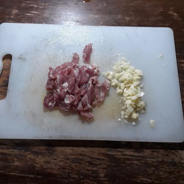Cincang bawang putih dan potong kecil daging.
