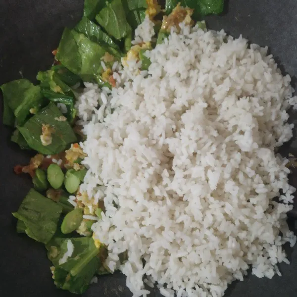 Masukkan sawi dan nasi putih, aduk merata.