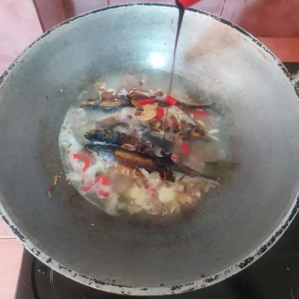 Tuang air, masukkan ikan. Beri kecap manis.
