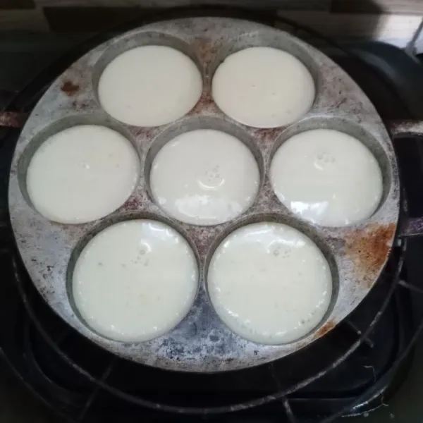 Panaskan cetakan dengan api besar sampai cetakan ketika dipercikinair mendesis. Kemudian kecilkan api hingga cenderung sedang ke kecil. Tuang 1/2 bagian adonan putih.