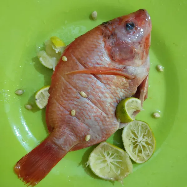 Cuci bersih ikan nila, beri perasan jeruk nipis. Diamkan selama 10 menit, cuci kembali hingga bersih, tiriskan.