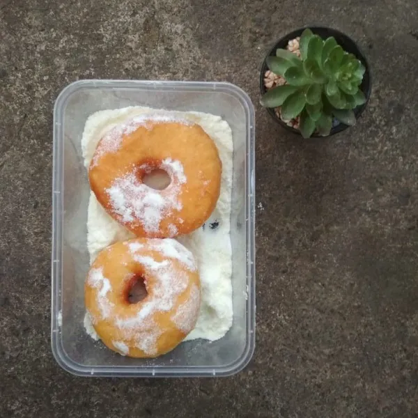 Gulingkan donat di campuran gula dan susu bubuk, tata di piring saji