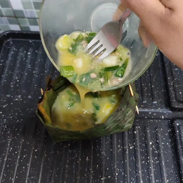 Tuang bahan telur ke atas daun pisang.