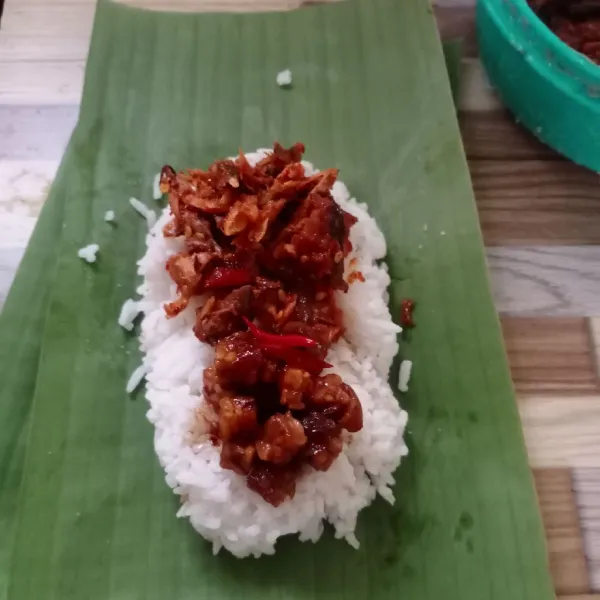 Ambil 1 lembar daun pisang. Beri 1 centong nasi. Beri tempe orek dan tongkol suwir diatasnya. Kemudian lipat.