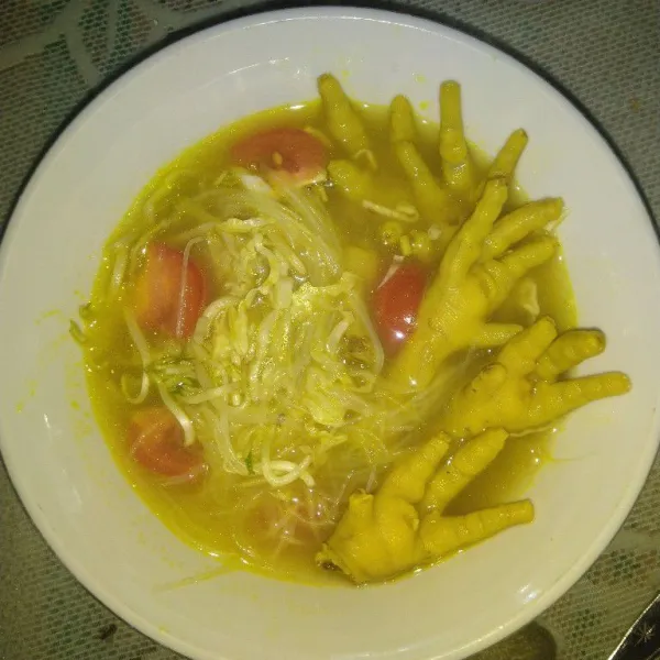 Tata soun, kol, tauge, tomat, dan ceker ayam di atas mangkuk saji. Kemudian siram dengan kuah yang panas.