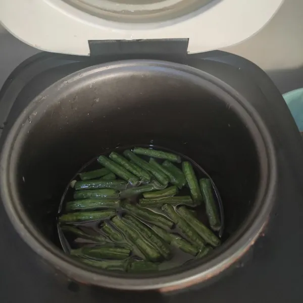 Potong memanjang kacang panjang, kemudian rebus hingga matang.