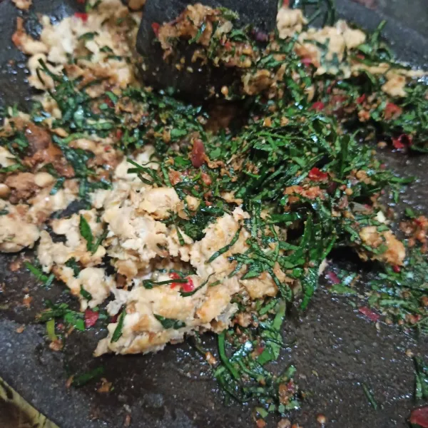 Masukkan tempe, lalu penyet. Tambahkan daun sembukan, aduk rata.