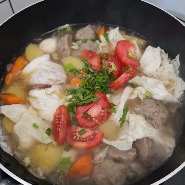 Tambahkan tomat, daun bawang, dan daun seledri. Aduk kembali, masak sebentar saja. Koreksi rasa dan sajikan.