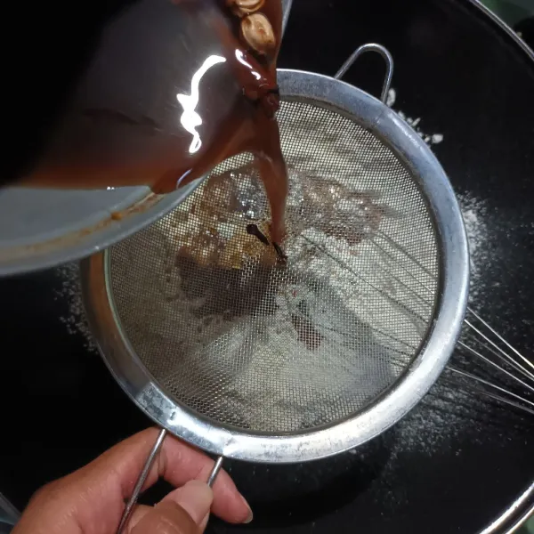 Tuangkan dan saring air rebusan rempah-rempah ke dalam wadah yang berisi tepung terigu secara bertahap.