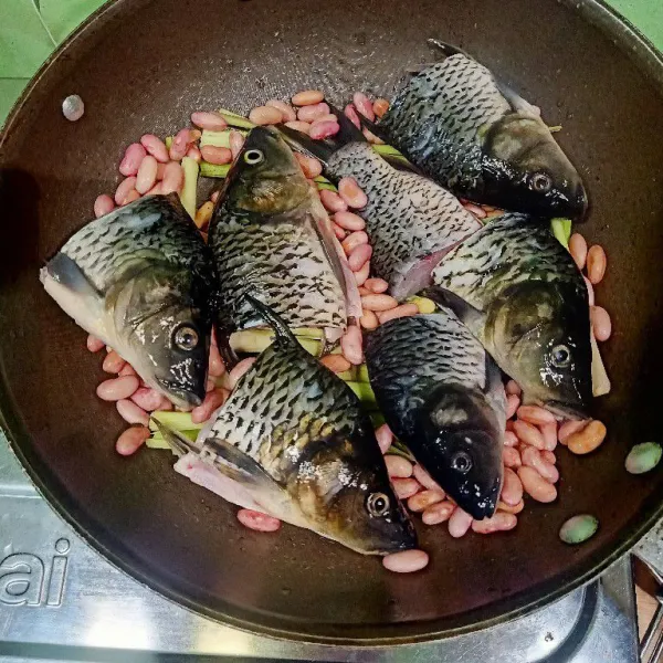 Tata di wajan bagian bawah serai lalu masukkan kacang merah dan ikan mas.