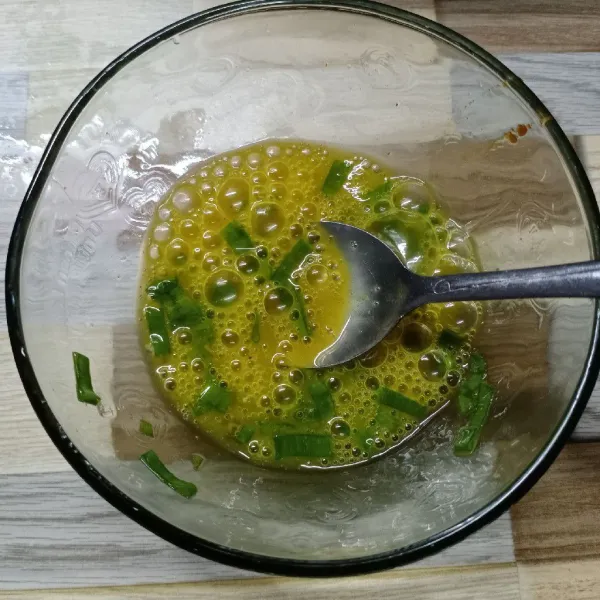Dalam wadah masukkan telur, daun bawang, garam dan lada bubuk. Kocok rata.