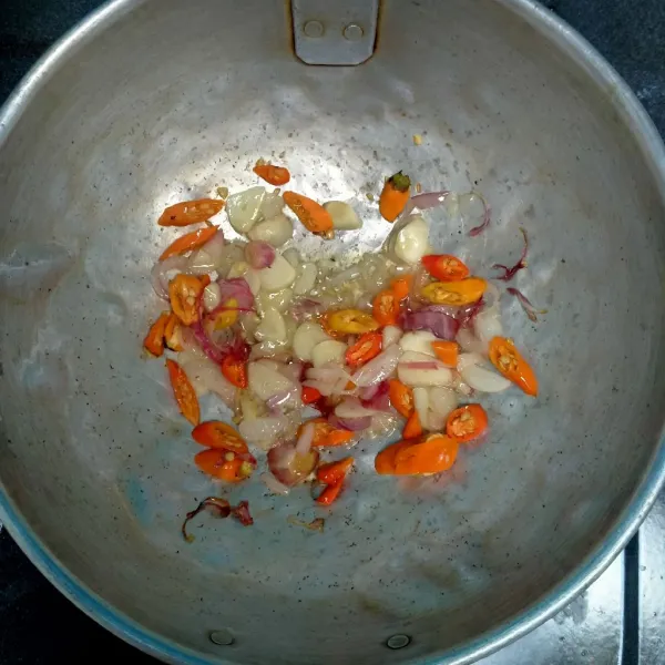 Panaskan minyak tumis bawang merah, bawang putih, dan cabe rawit .