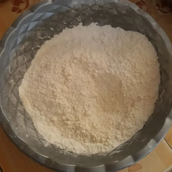 Campurkan tepung terigu, tepung beras, gula pasir, baking powder, dan ragi. Aduk rata