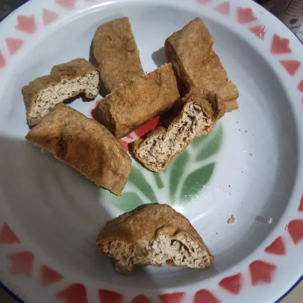 Belah tahu menjadi dua, kemudian kerok isinya.