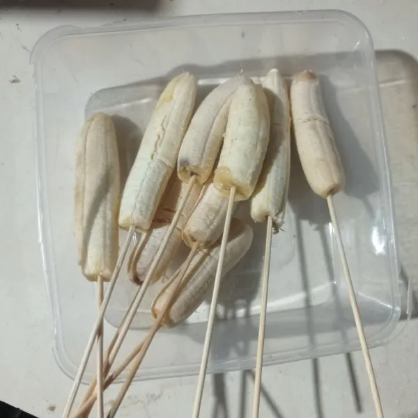 Kupas pisang, tusuk menggunakan tusuk sate.