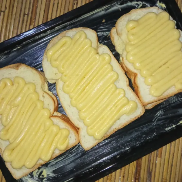 Susun roti di loyang oven, semprotkan adonan topping tadi ke atas roti.
