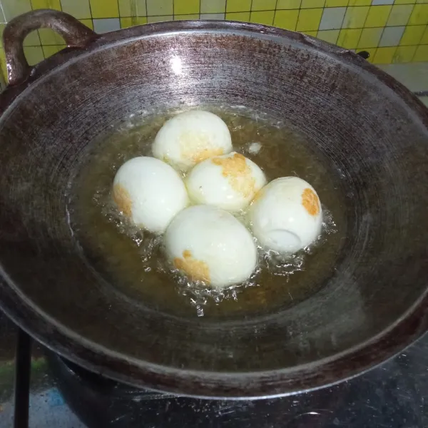 Kupas telur, beri beberapa sayatan, lalu goreng hingga berkulit. Sisihkan.