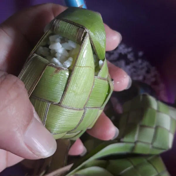 Masukkan beras ketan dalam sarang ketupat sampai 3/4 bagian.