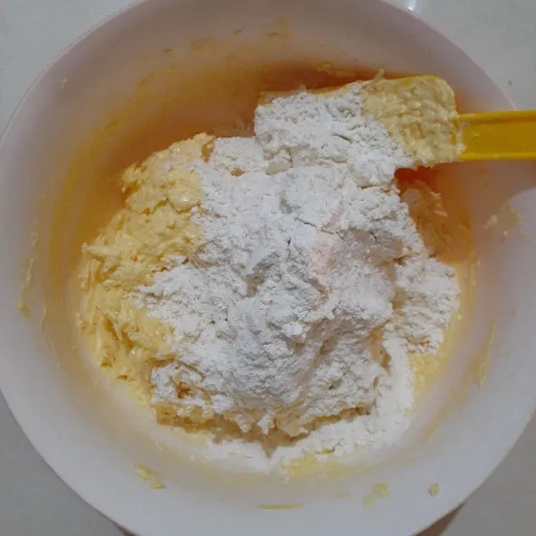 Tambahkan campuran tepung dan susu bubuknya, sedikit demi sedikit, aduk merata dengan spatula.