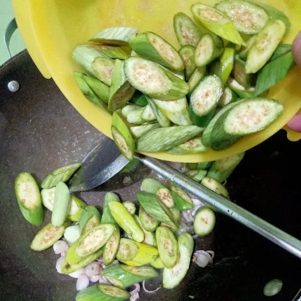 Masukkan irisan terong telunjuk ke dalam wajan.