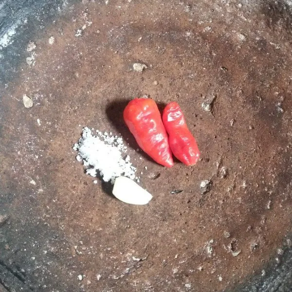 Siapkan cobek, haluskan cabe, bawang putih, dan garam.