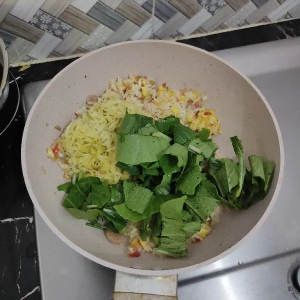 Masukkan mie, sawi, dan daun bawang lalu aduk rata.